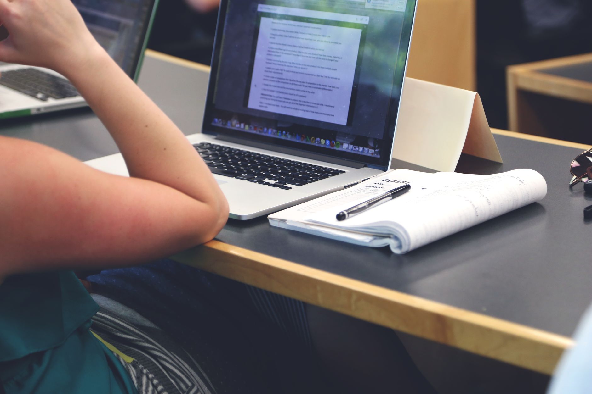 A student following an online lesson on a laptop with a notebook open
