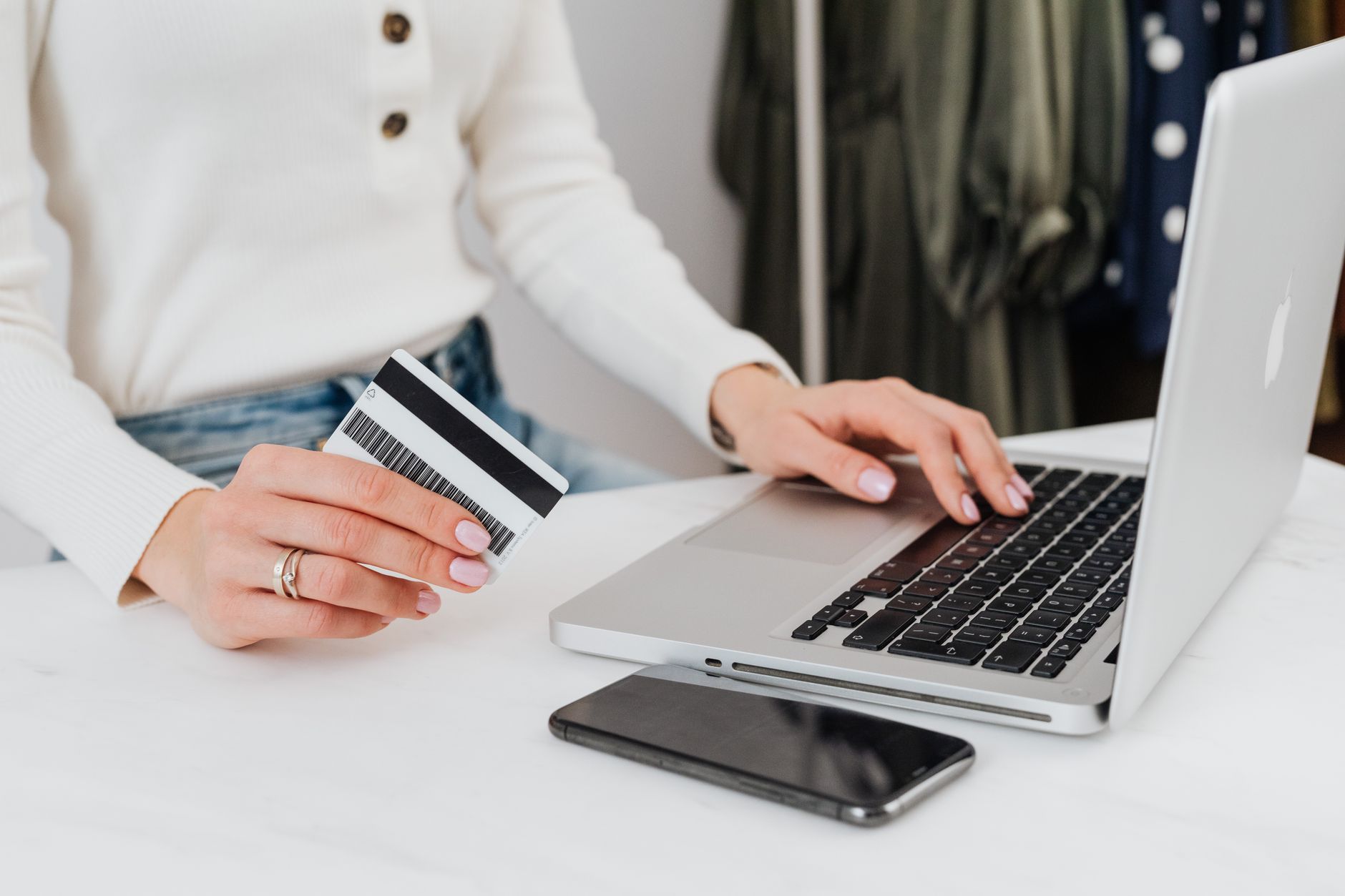 Someone paying online with a card beside a laptop